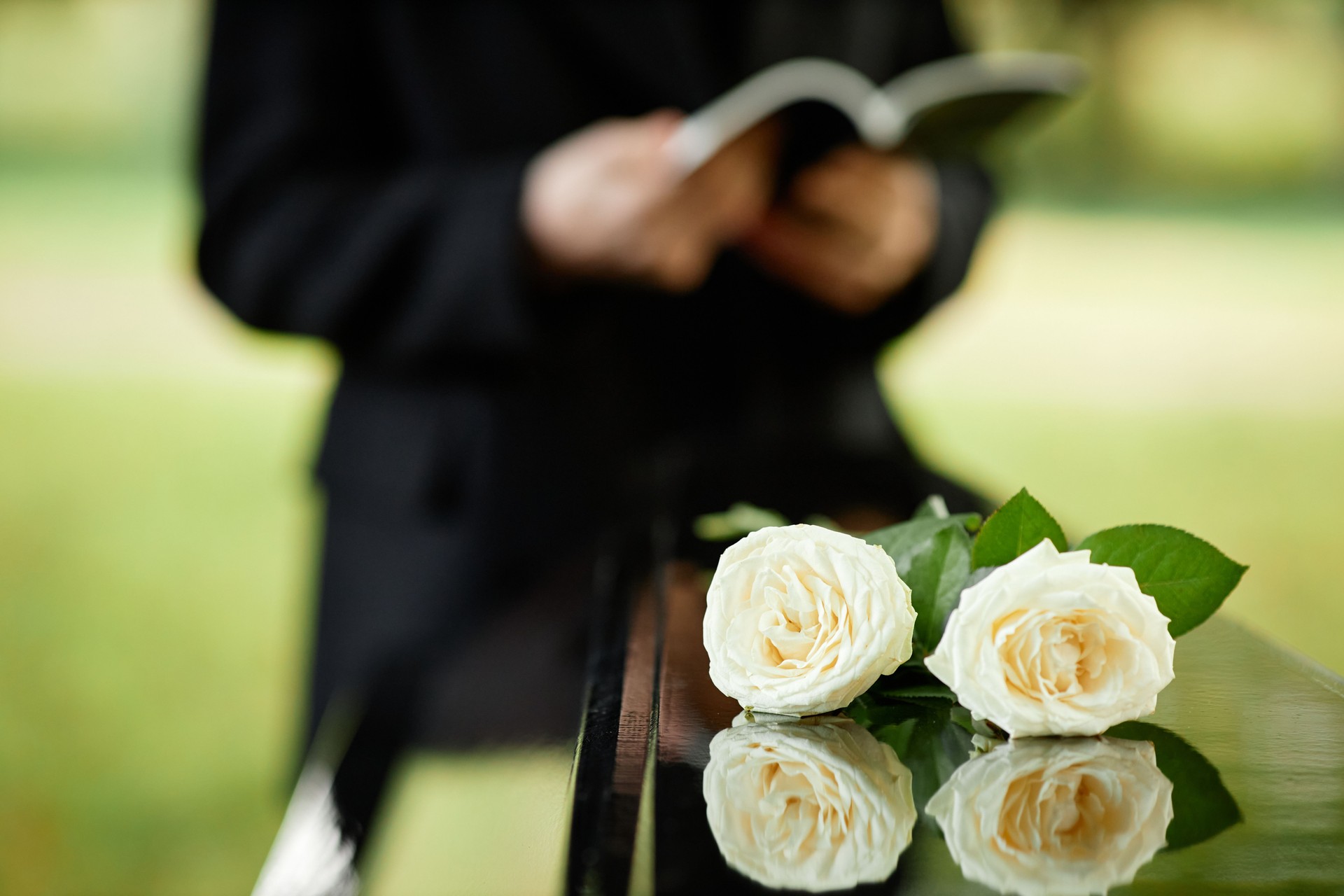 Closeup of two white roses on coffin at funeral ceremony